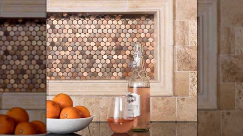 Copper penny tile backsplash with ceramic tile boarder behind a black counter with a drink and oranges