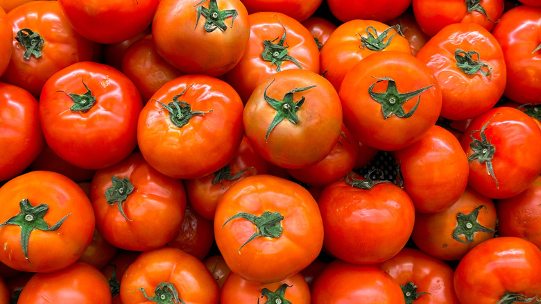 Shiny orange celebrity tomatoes are piled on top of each other.