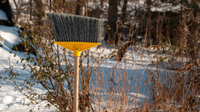 upside down broom outside in front of snow and branches