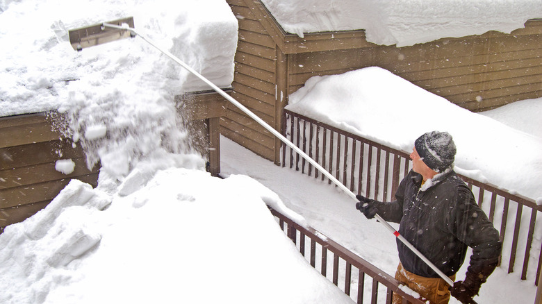 Person using a roof rake to clear snow from roof