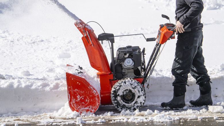 Person pushing a snow blower to clear snow