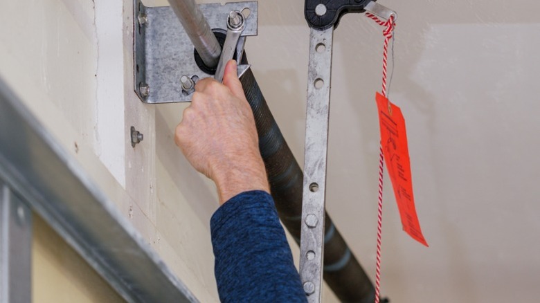 Hand fixing garage door spring with wrench