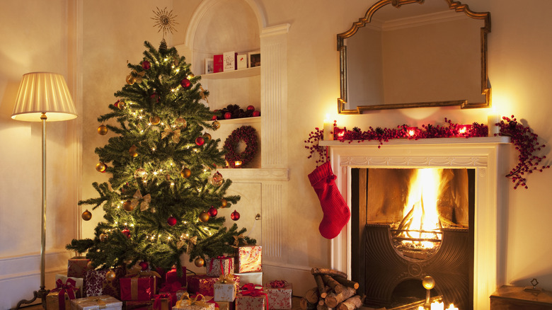 A cozy Christmas decorated living room with an open fireplace, a tree, garlands, and a stocking