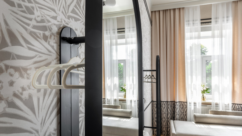 A mirror reflecting the view from the window opposite it