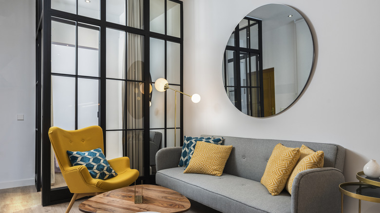 Modern living room with stylish furniture and a large mirror hung over the sofa