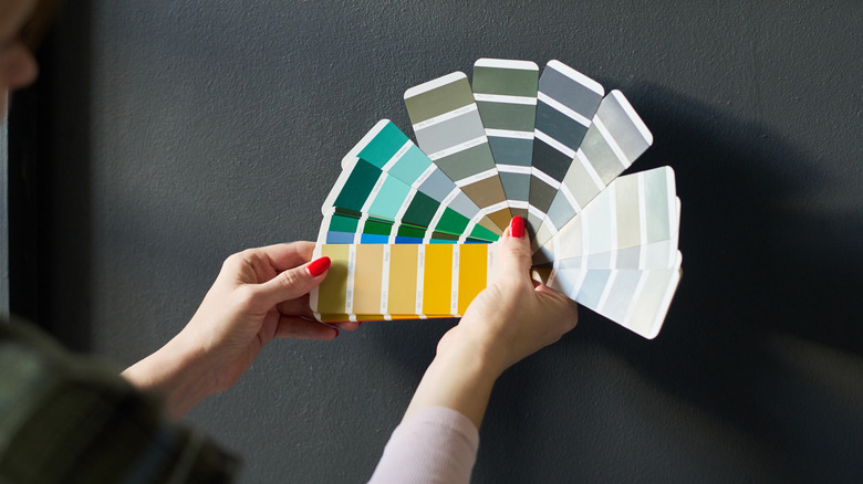 Woman holding a color palette against a dark gray wall