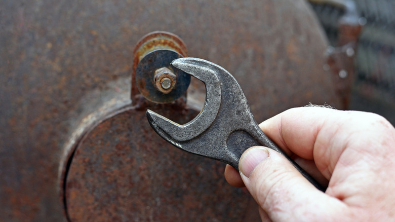 person using wrench on rusted bolt