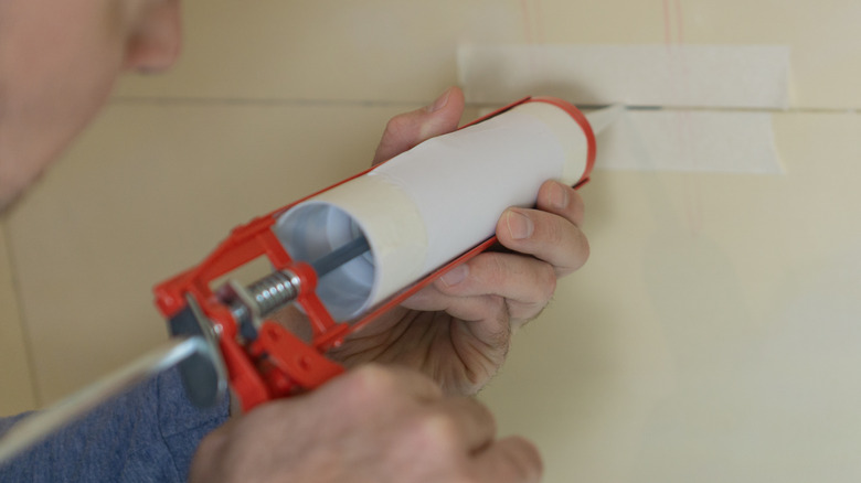 closeup on man holding caulking tube