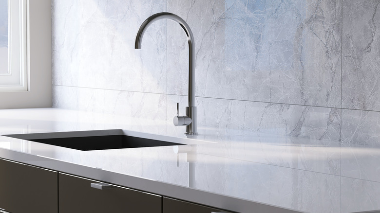 Minimalist kitchen with white laminate countertops, tall faucet, and dark accents