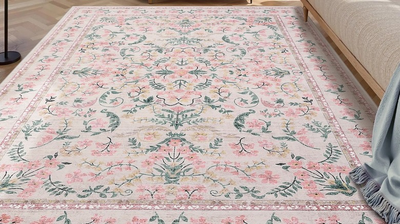 Closeup of a pink floral Winston Porter rug in a living room