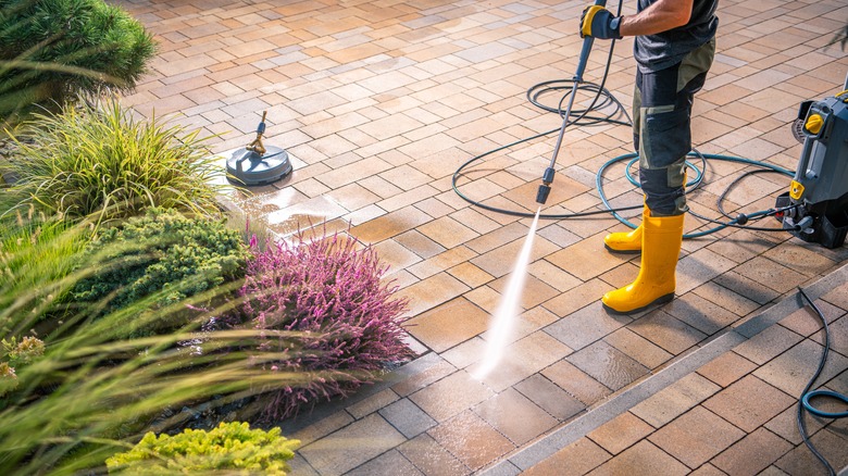 Someone pressure washing a patio in yellow boots.