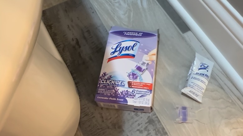 A Lysol Click Gel Automatic Toilet Bowl Cleaner applicator on the floor.