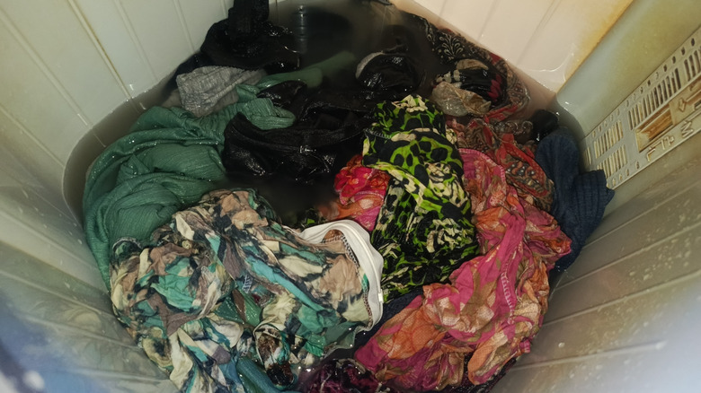 A pile of water logged clothes inside a washing machine drum.