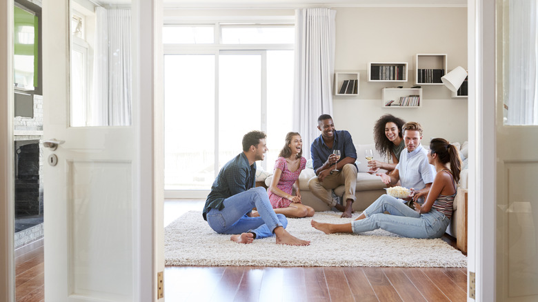 A group of friends relax on the floor in a living room