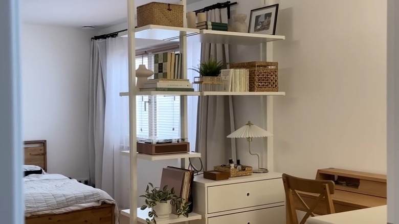 IKEA ELVARLI shelving system separates a work nook in a bedroom.