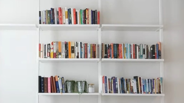 White ELVARLI shelves hold books against a white wall, creating a floating shelf illusion.