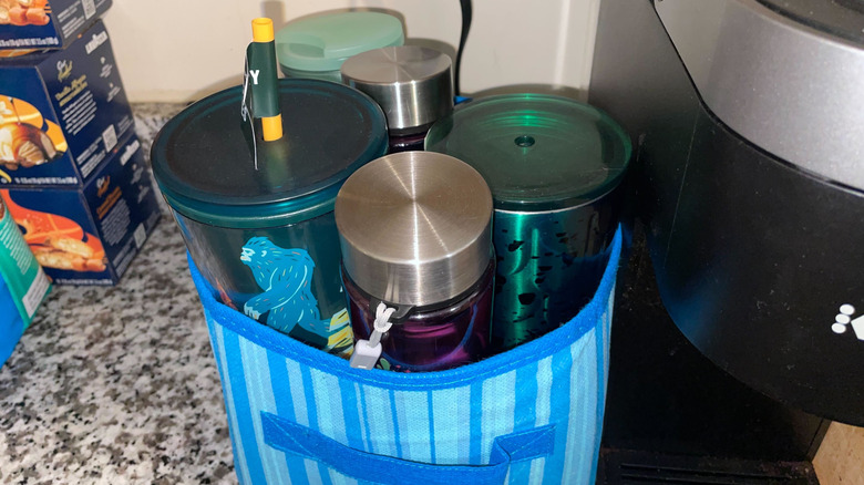 Tumblers in a fabric bin next to a coffee maker