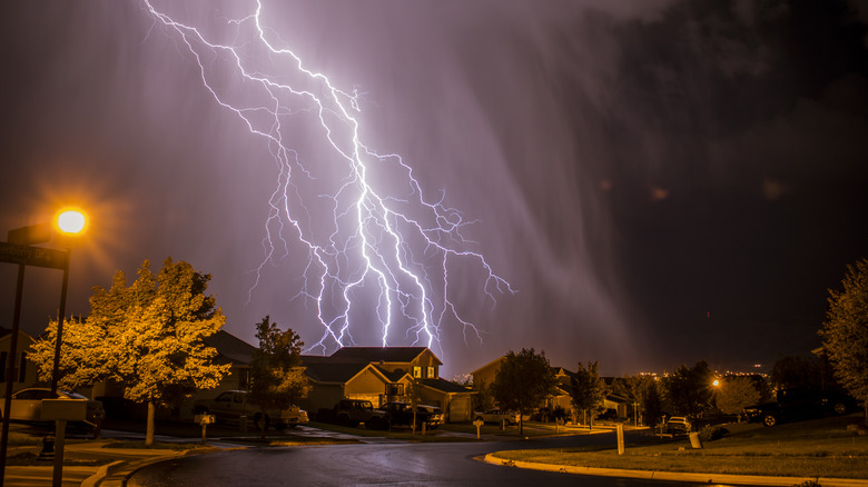 Lightning striking the ground near suburban homes at night.