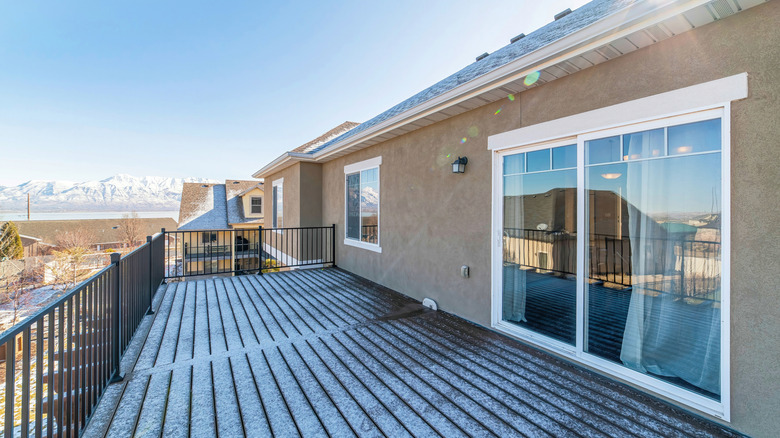 The outside of a sliding glass door that opens up to a deck with a slight snow on it.