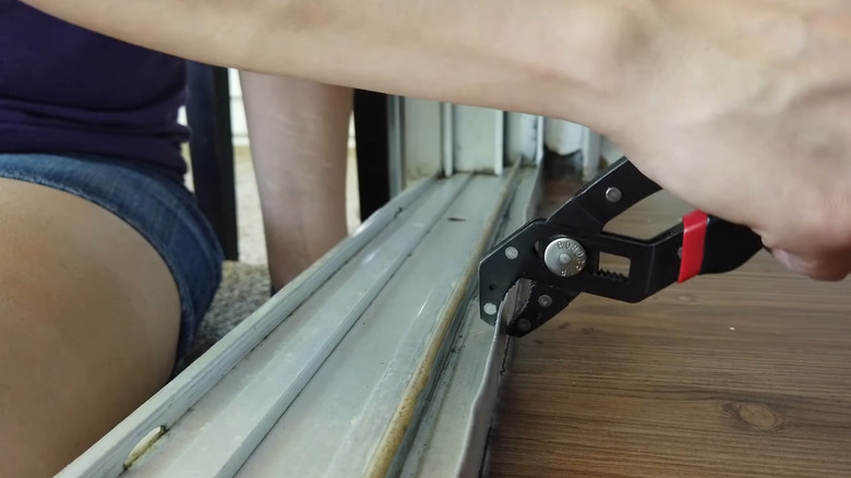 Hands using pliers to pend a track back into alignment.