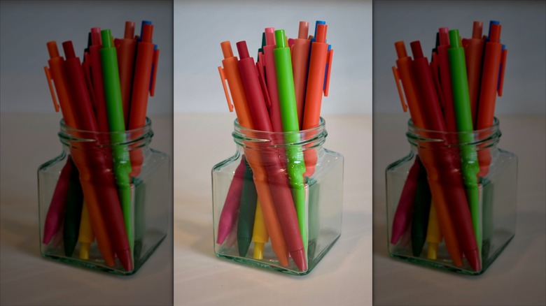 Colorful pens in a small glass vase