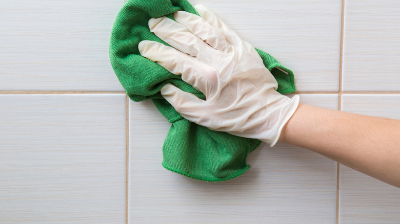 Closeup of gloved hand cleaning tile with rag