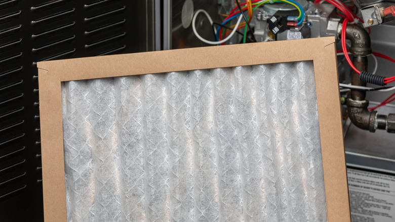 Clean air filter being held in front of furnace