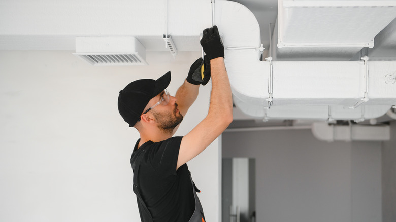 HVAC worker checking ducts in a home