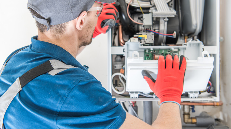 HVAC tech inspecting a furnace, he pulls the control panel cover down