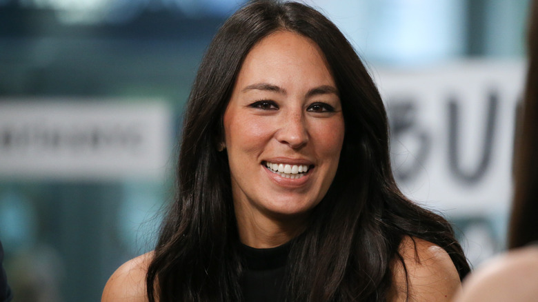 Joanna Gaines smiling in a black top with long loose hair