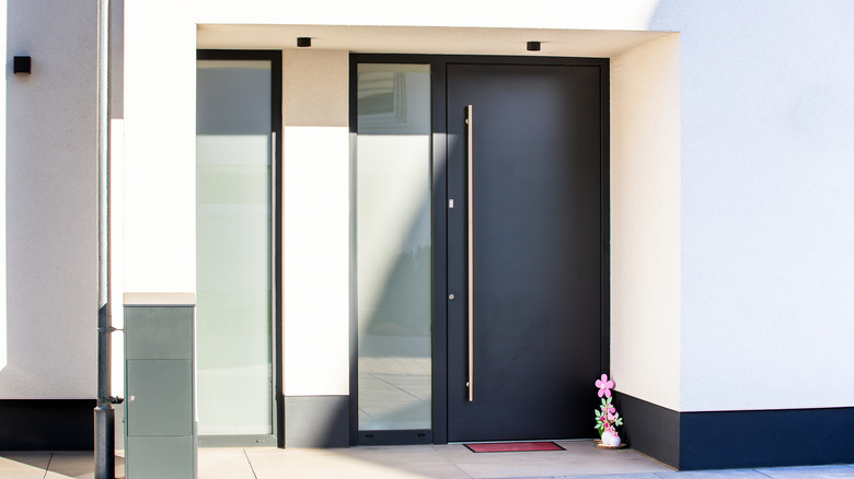 Modern and sleek anthracite black front door with frosted glass on the side of it.