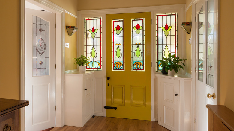 Front door and hallway of a house with stained glass window in the door.