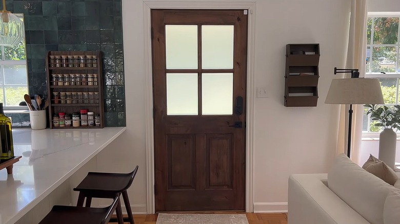 Dark wooden front door with a four-panel window covered in privacy film