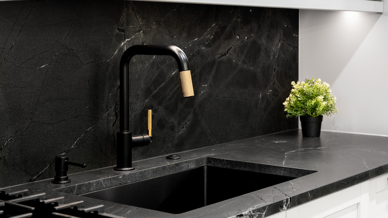 Black kitchen sink with black stone backsplash and countertop