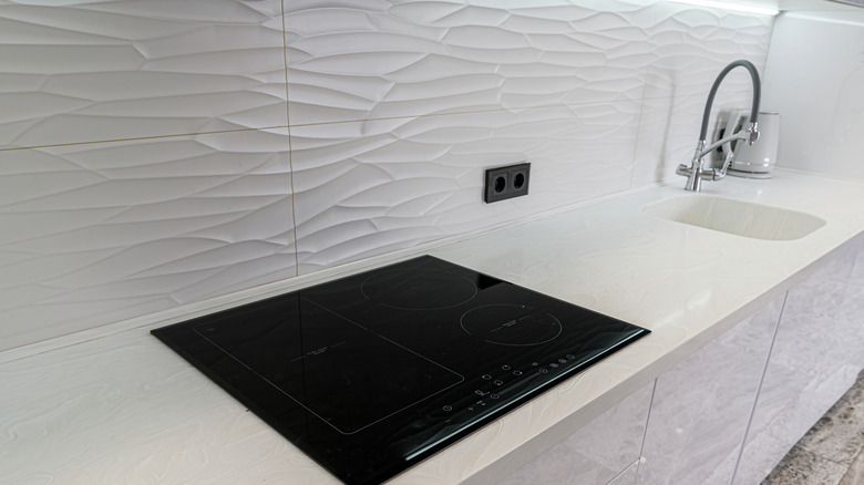 3D tiles covering a backsplash over a kitchen stovetop and sink