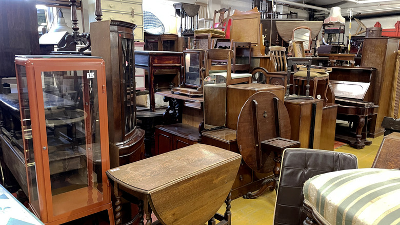 Furniture area of thrift store, showing many types of wood furniture, including tables, chairs, and cabinets