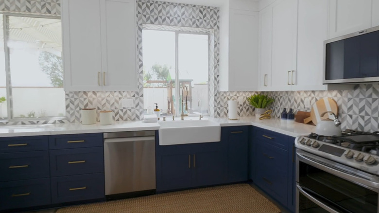 A bright kitchen with blue cabinets and chevron tiles.