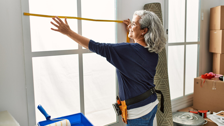 Person measuring a window for treatments