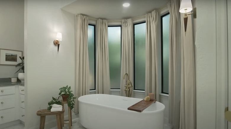A modern bathroom with a tub and large windows.