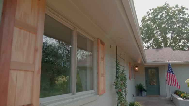 Two men putting up shutters on a house.