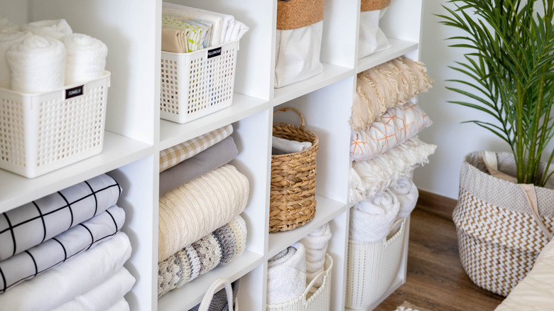 A linen closet with neatly stacked linen and baskets to hold smaller items.
