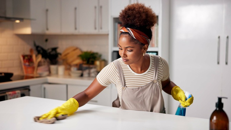 Woman with a spray bottle cleaning a kitchen counter