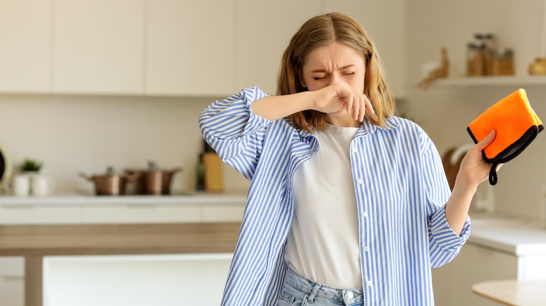 woman sneezing while cleaning kitchen