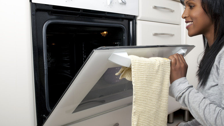 happy woman peering into clean open oven