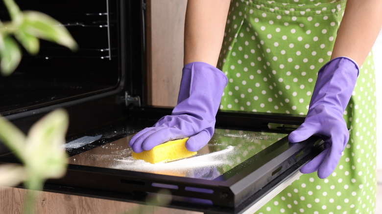 hands cleaning oven with rubber gloves