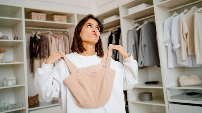 A girl holding up top making a decision