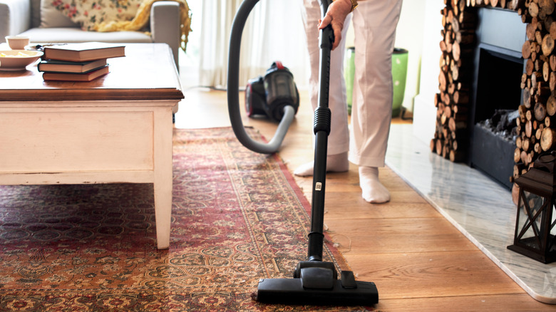 Person vacuuming an area rug in living room