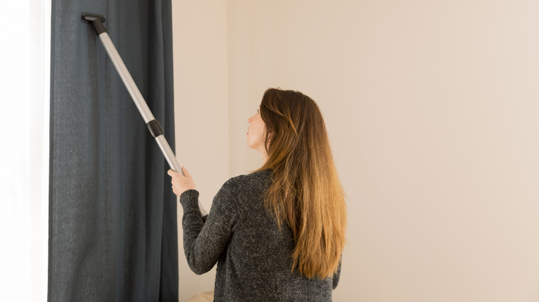 Woman vacuuming dark drapes
