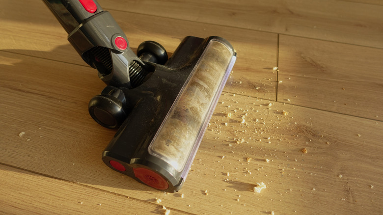Vacuum picking up crumbs on light colored hardwood floor
