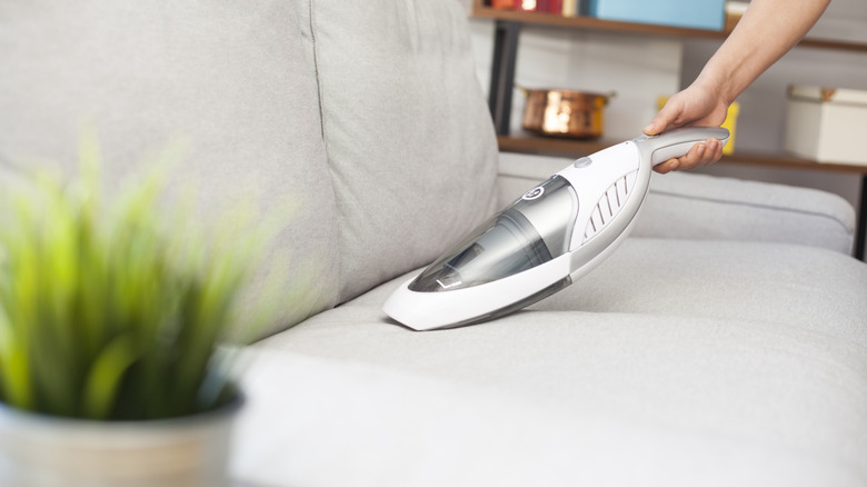 Hand-held vacuuming light colored couch